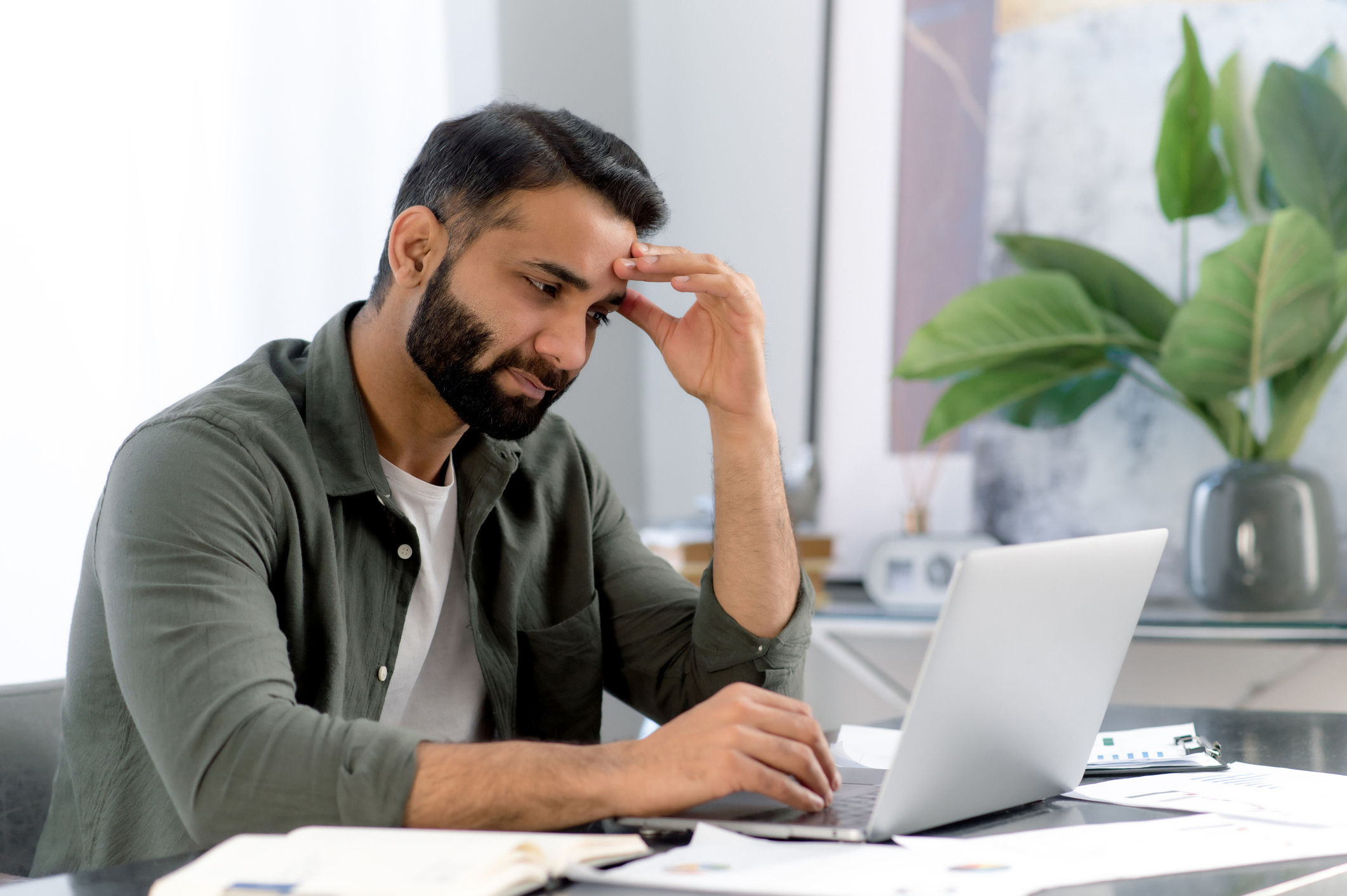 Man working at a laptop surrounded by papers